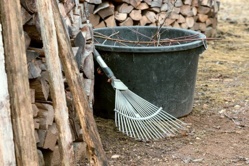 Metal garden rakes lying on the wooden walls.