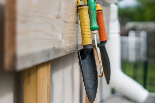 Gardening tools are hanged on the wall.